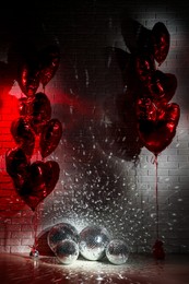 Photo of Many shiny disco balls in room decorated with heart shaped balloons, color toned