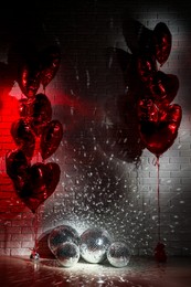 Many shiny disco balls in room decorated with heart shaped balloons, color toned