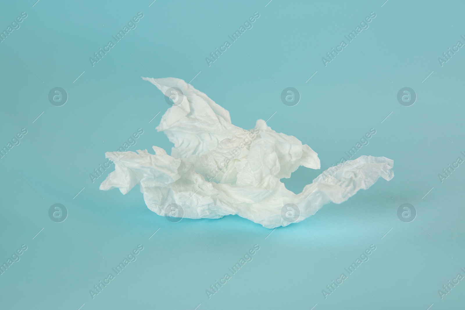 Photo of Used paper tissue on light blue background, closeup