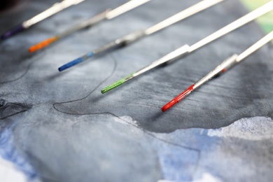 Photo of Tattoo needles with ink on painted paper, closeup