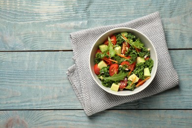 Photo of Tasty fresh kale salad on light blue wooden table, flat lay. Space for text