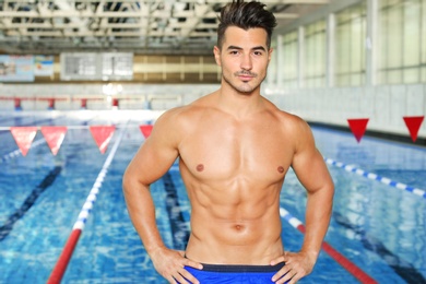 Young athletic man near swimming pool indoors