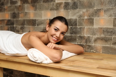Young woman lying on wooden bench in salt sauna. Spa treatment