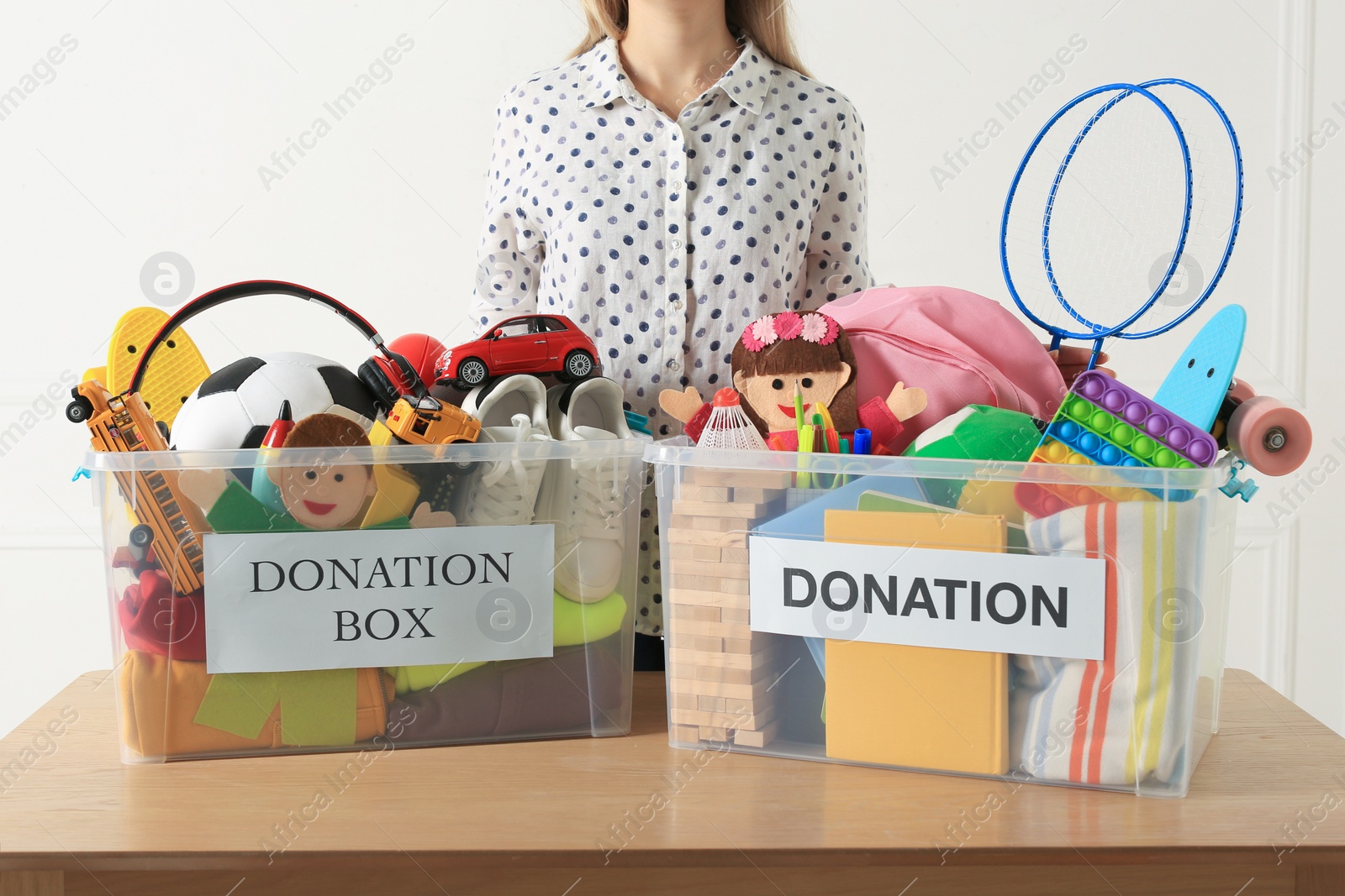 Photo of Woman near donation boxes with child toys against white background, closeup