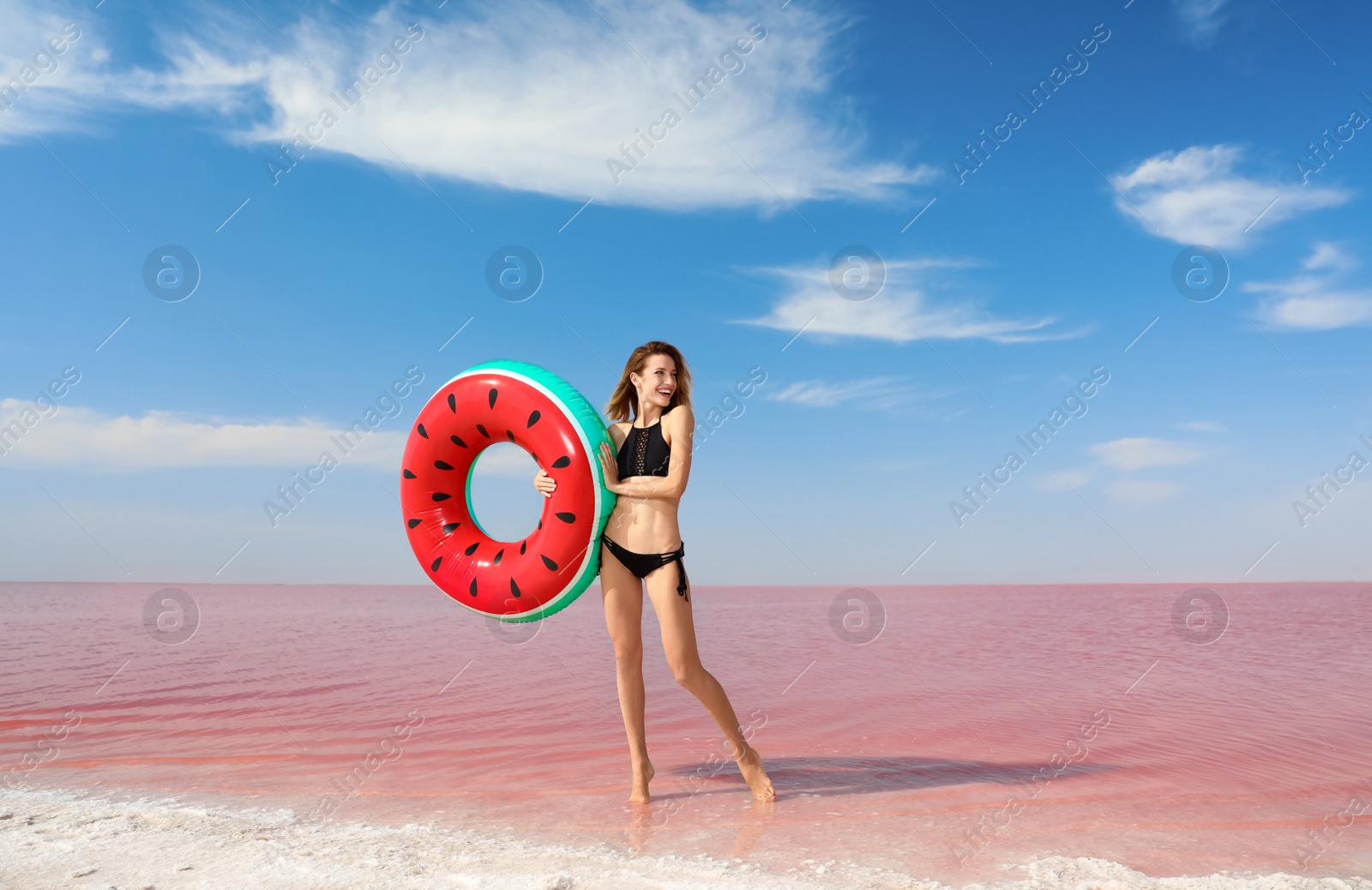 Photo of Beautiful woman with inflatable ring posing near pink lake on sunny day