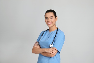 Portrait of young medical assistant with stethoscope on color background