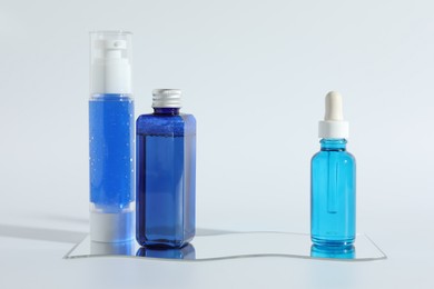 Different containers with cosmetic products on light background