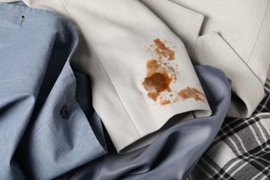 Photo of Dirty shirts and jacket with stain of coffee as background, closeup