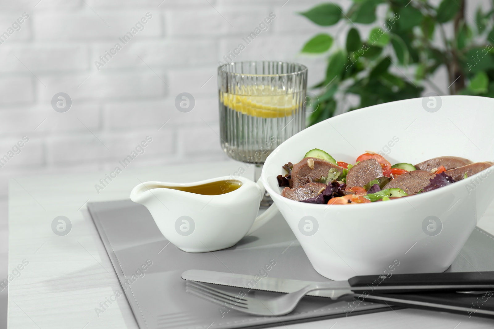 Photo of Delicious salad with beef tongue and vegetables served on white wooden table. Space for text