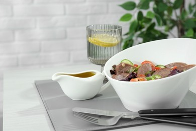 Delicious salad with beef tongue and vegetables served on white wooden table. Space for text