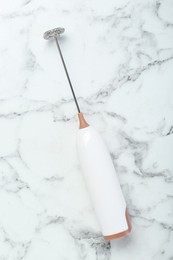 Milk frother wand on white marble table, top view