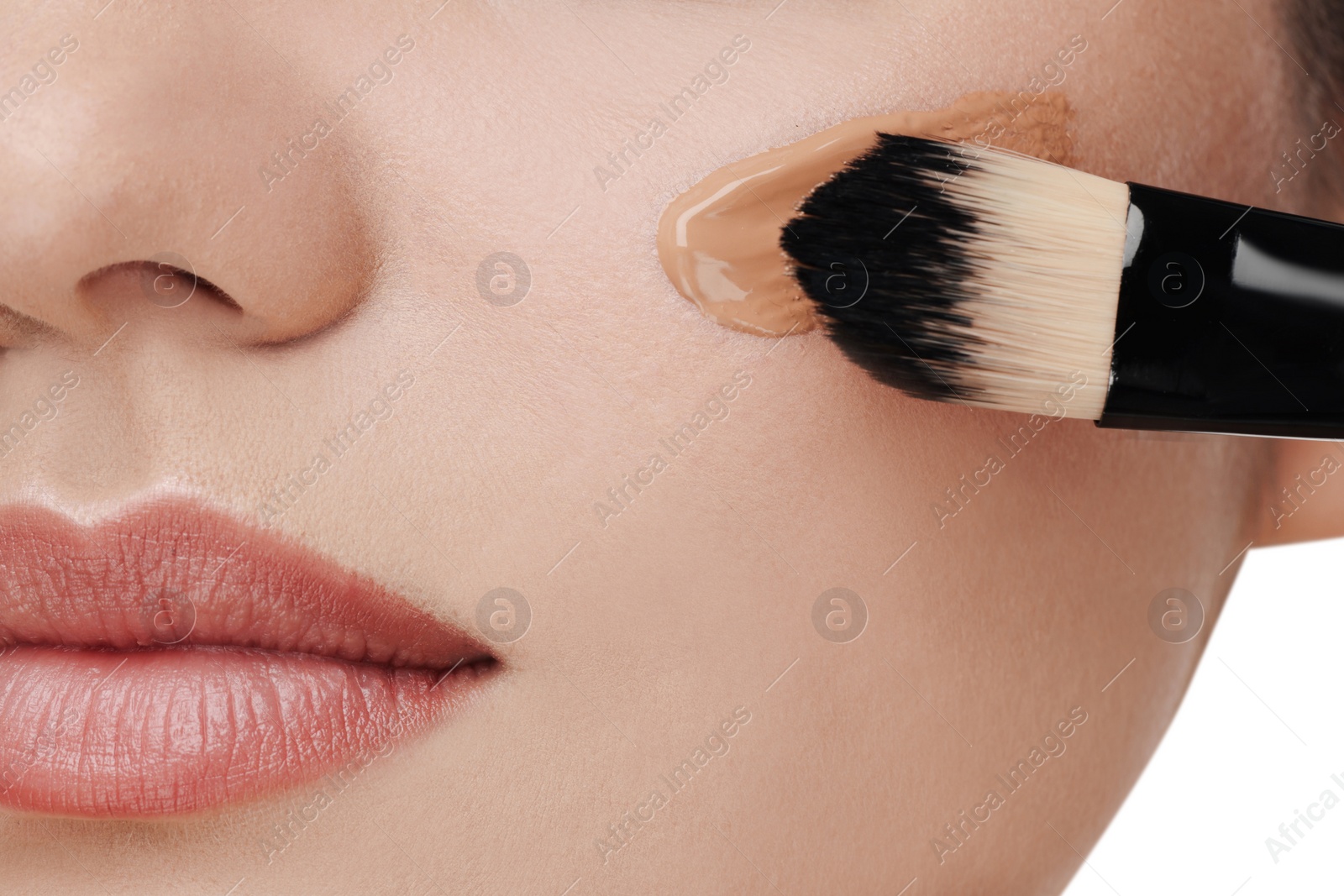 Photo of Woman applying foundation on face with brush against white background, closeup