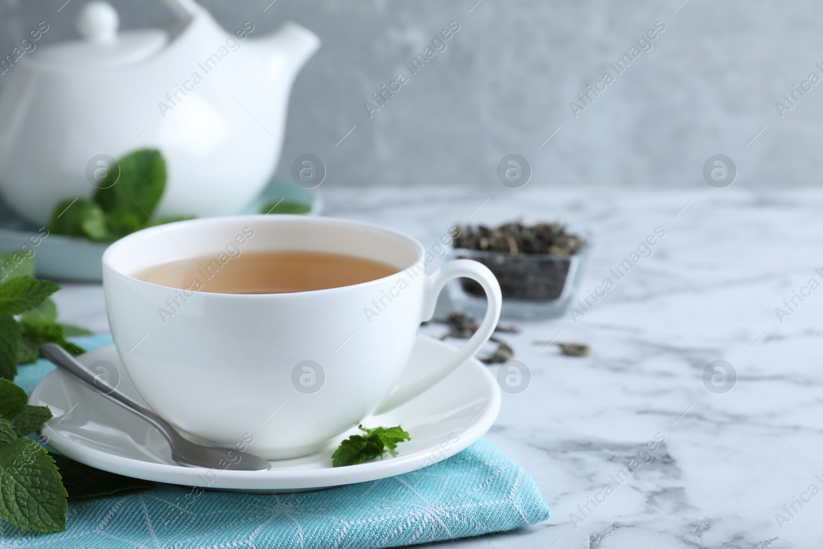 Photo of Fresh tea with mint on white marble table. Space for text