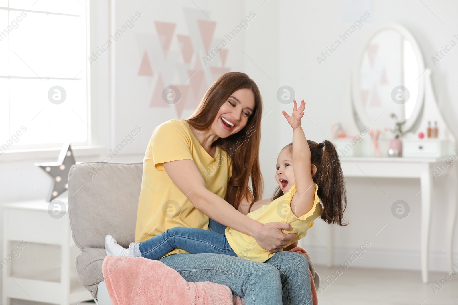 Photo of Young mother with little daughter having fun at home