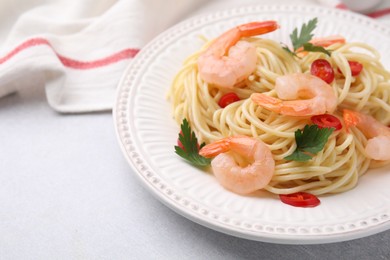 Photo of Tasty spaghetti with shrimps, chili pepper and parsley on grey table, closeup. Space for text