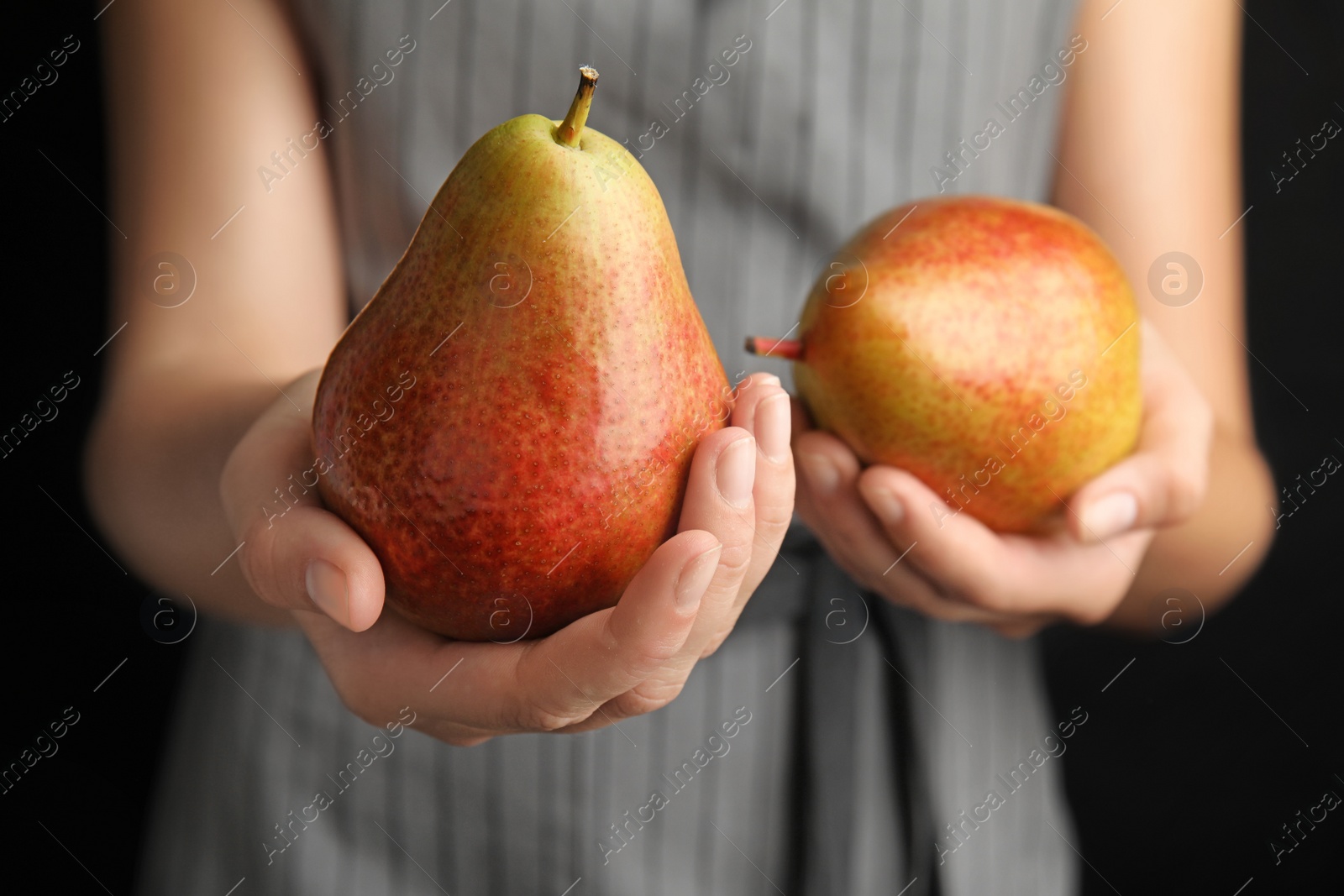 Photo of Woman holding ripe juicy pears on black background, closeup