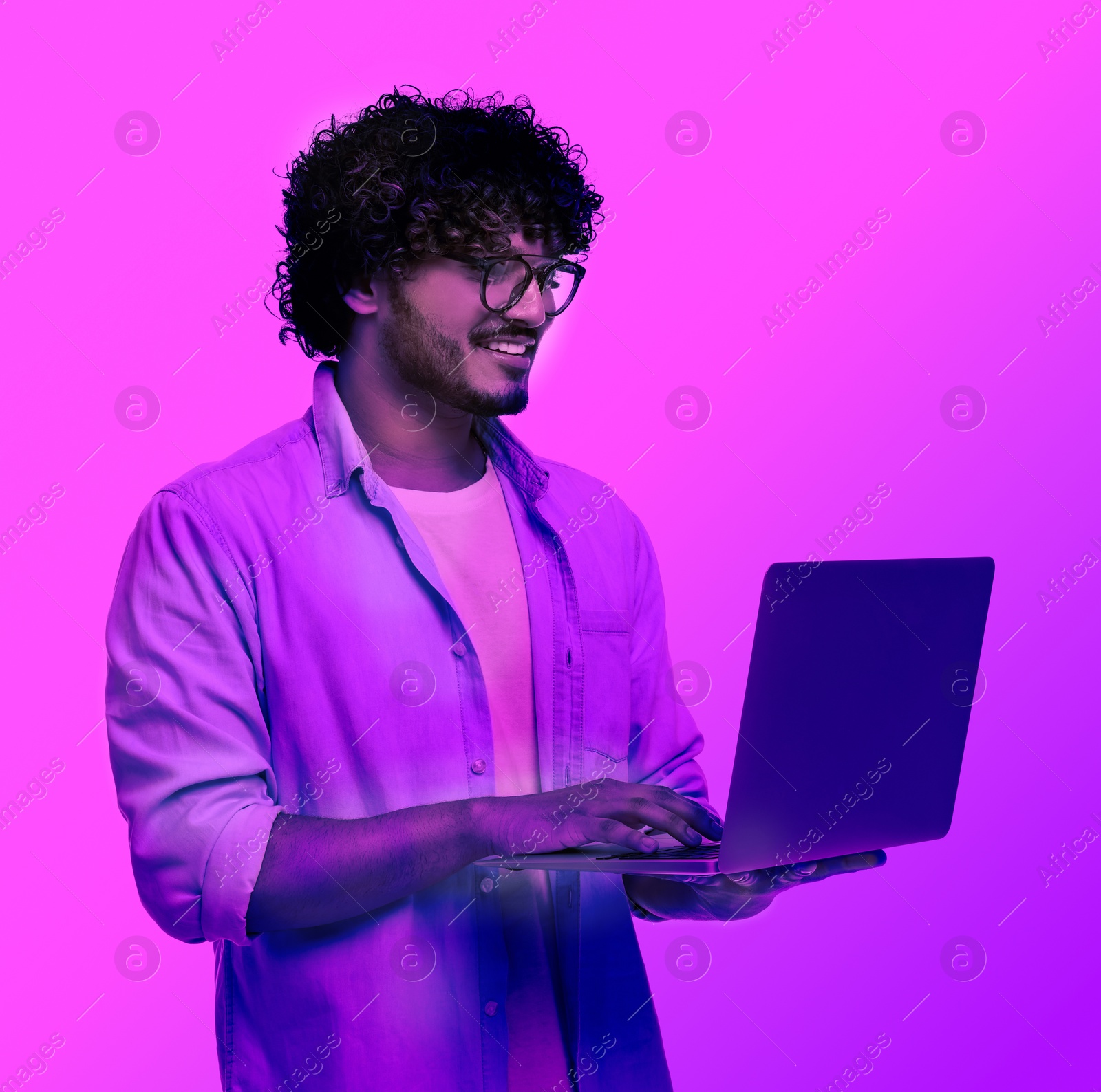 Image of Handsome man with laptop in neon lights