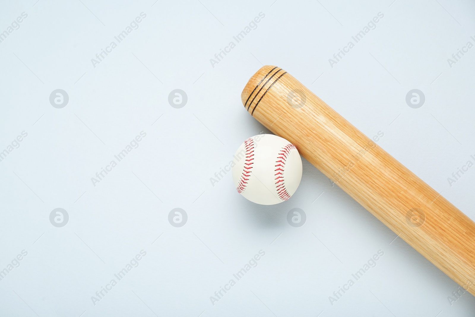 Photo of Wooden baseball bat and ball on light grey background, flat lay. Space for text