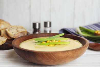 Photo of Delicious corn cream soup served on white wooden table