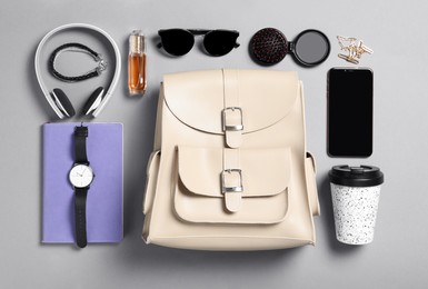 Photo of Stylish urban backpack with different items on grey background, flat lay