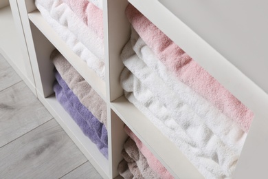 Photo of Colorful towels on shelves, closeup. Bathroom supplies