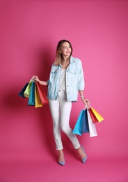 Photo of Beautiful young woman with shopping bags on color background