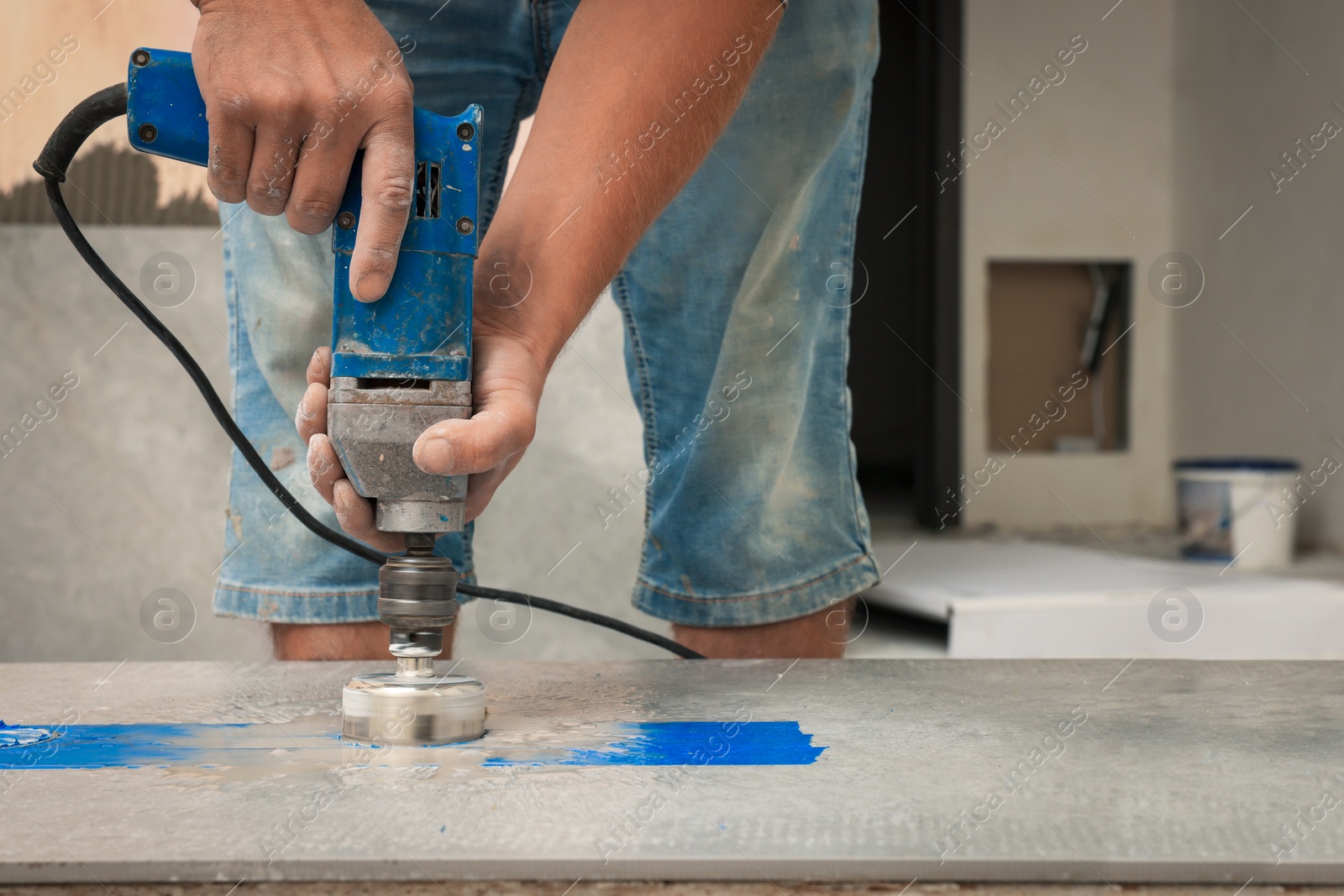 Photo of Worker making socket hole in tile indoors, closeup