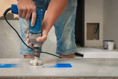 Worker making socket hole in tile indoors, closeup