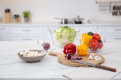 Different fresh vegetables and mushrooms on white table in modern kitchen