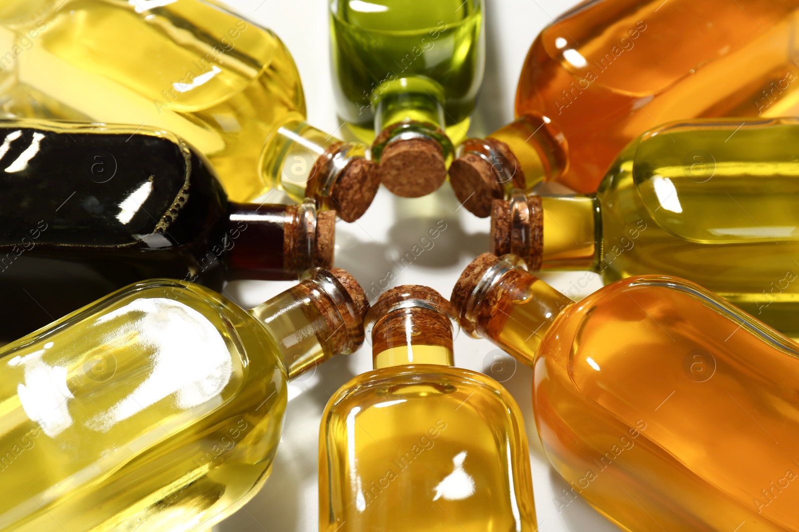 Photo of Vegetable fats. Different cooking oils in glass bottles on white background, closeup