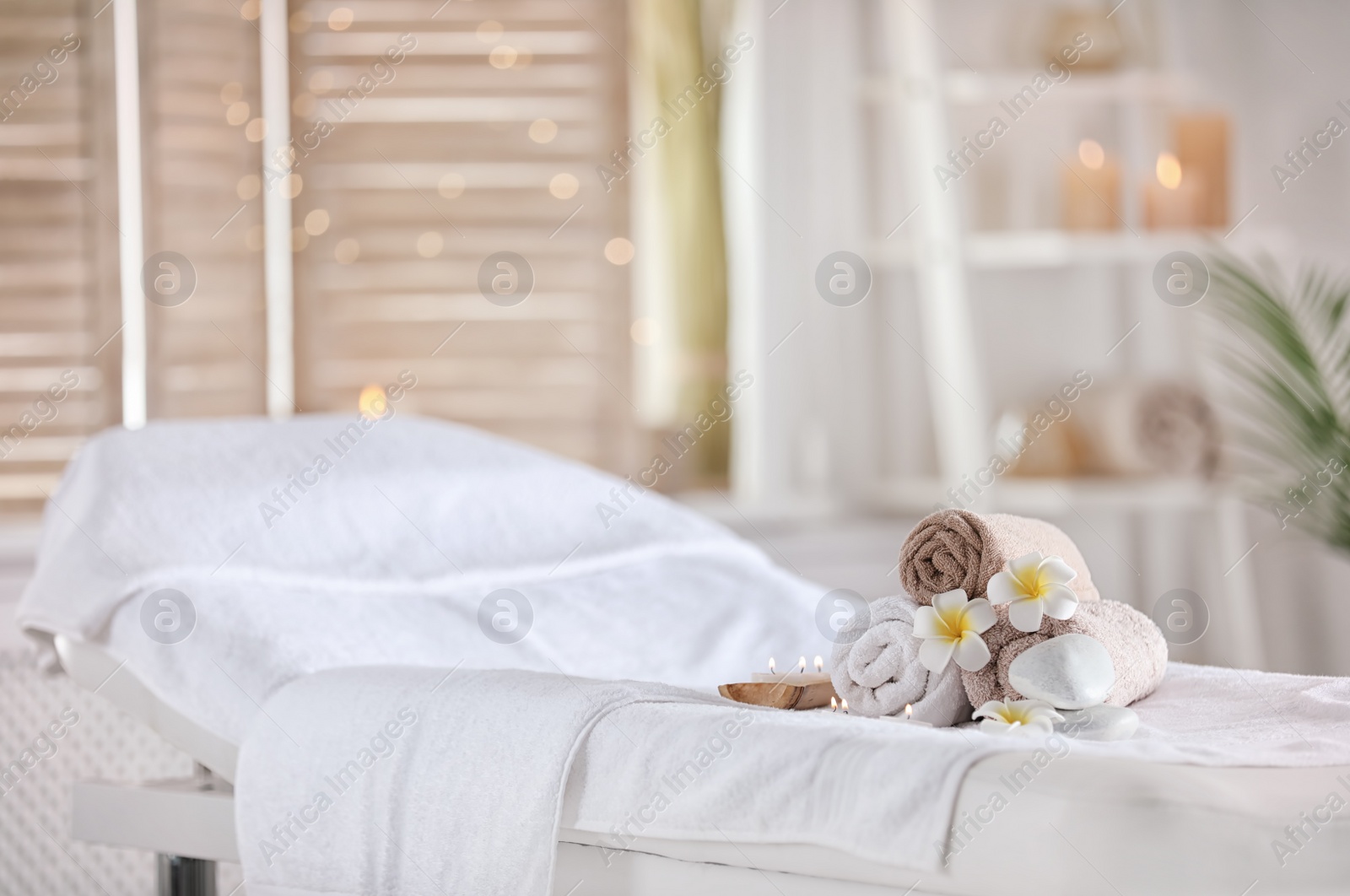 Photo of Towels and candles on massage table in modern spa salon. Place for relaxation