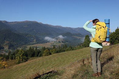 Photo of Tourist with backpack enjoying landscape in mountains on sunny day, back view