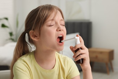 Photo of Little girl using throat spray at home