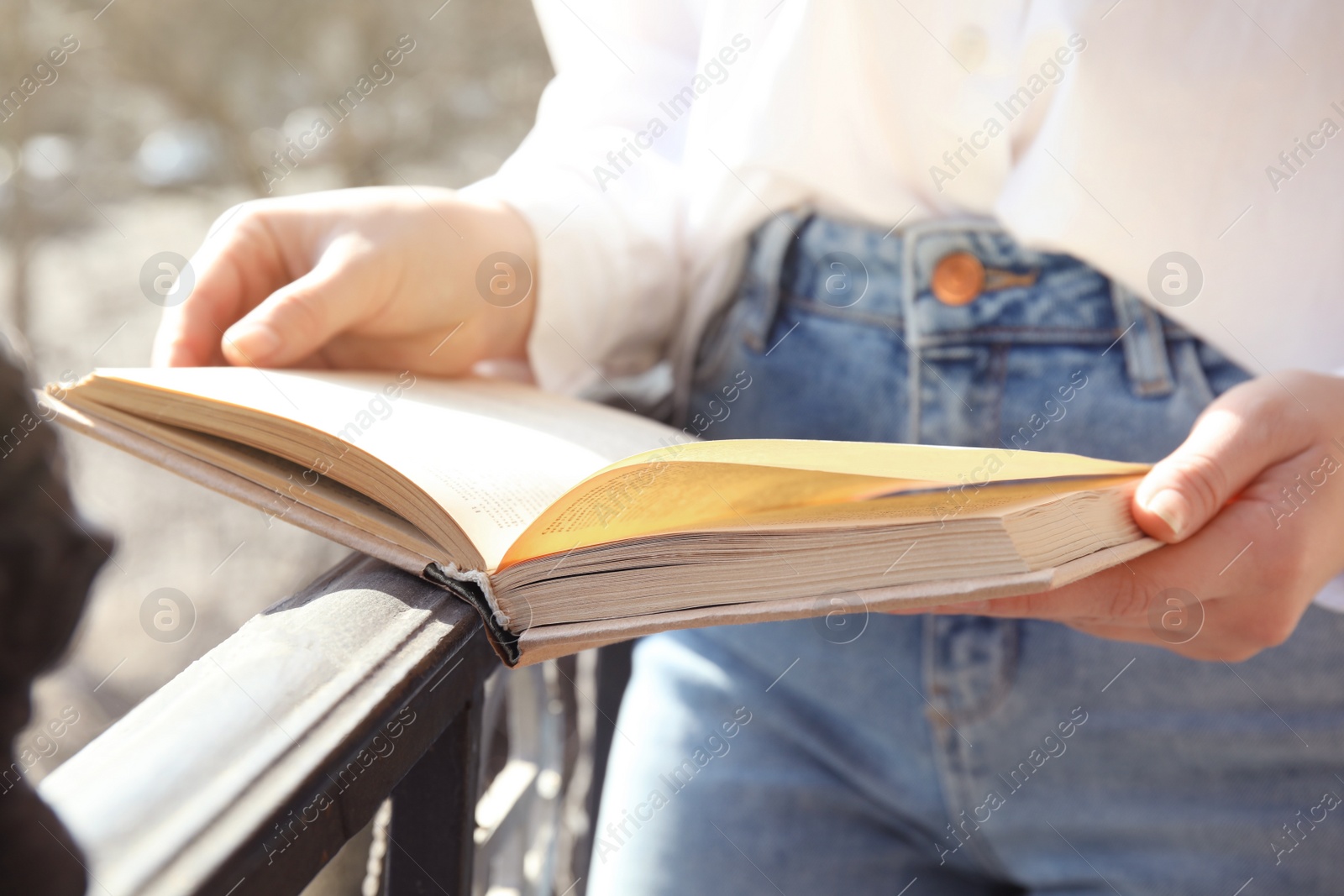 Photo of Woman reading book outdoors on sunny day, closeup