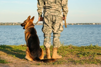 Photo of Man in military uniform with German shepherd dog outdoors, closeup