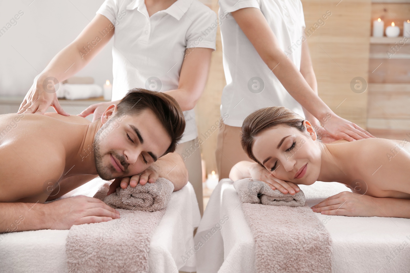 Photo of Romantic young couple enjoying back massage in spa salon