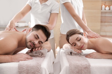 Romantic young couple enjoying back massage in spa salon