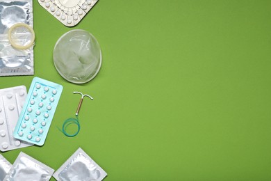 Photo of Contraceptive pills, condoms and intrauterine device on olive background, flat lay and space for text. Different birth control methods