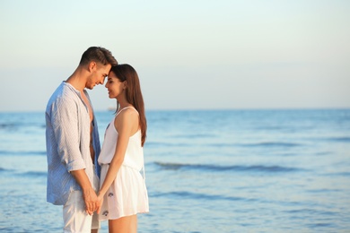 Happy young couple holding hands at beach on sunny day