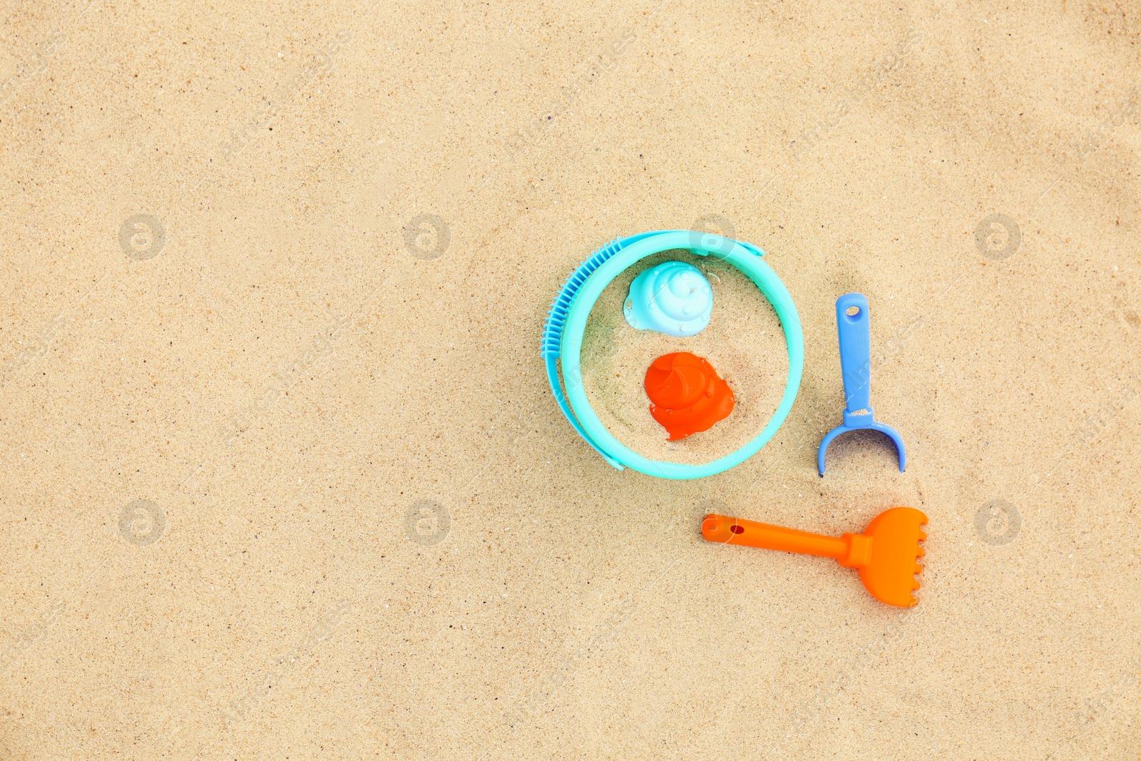 Photo of Set of plastic beach toys on sand, top view. Space for text