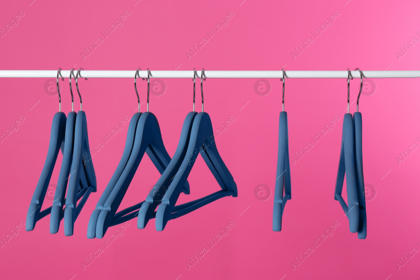 Photo of Metal rack with clothes hangers on color background