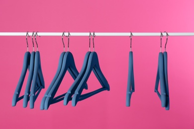 Metal rack with clothes hangers on color background