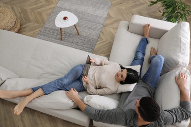 Photo of Couple with tablet resting on sofa in living room, above view