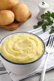 Photo of Bowl of tasty mashed potatoes served on grey table