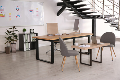 Stylish office interior with large wooden table