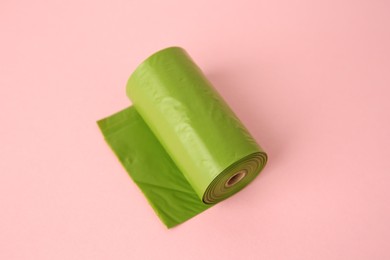 Photo of Colorful dog waste bags on pink background, above view