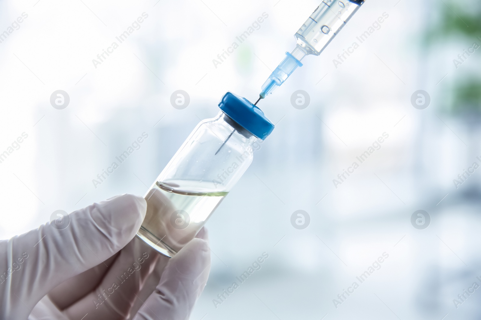 Photo of Doctor with syringe and medicine for vaccination on blurred background