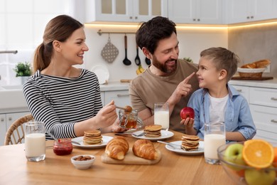 Photo of Happy family having fun during breakfast at table in kitchen