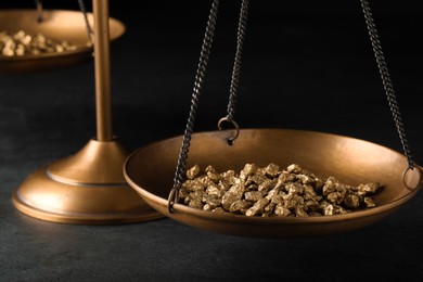 Photo of Vintage scales with gold nuggets on dark table, closeup