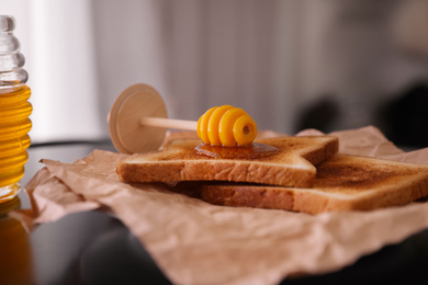 Photo of Delicious honey and toasts on parchment, closeup